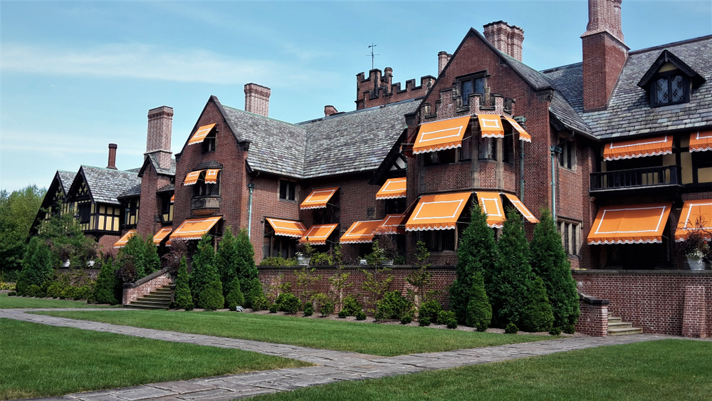 the exterior of a large brick manor house with bright orange awnings