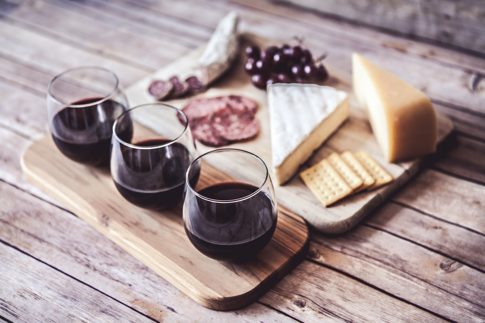 Wine on wooden board with cheese and grape in an article about wineries in Illinois. 
