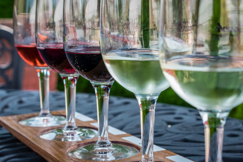 Wine glasses in a row with small amounts of wine in them.