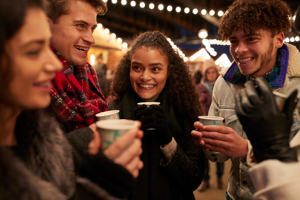 A group of young people in the winter outside drinking warm beverages