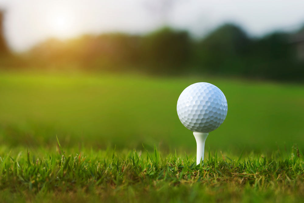 Close up photo of a white golf ball on a white tee.