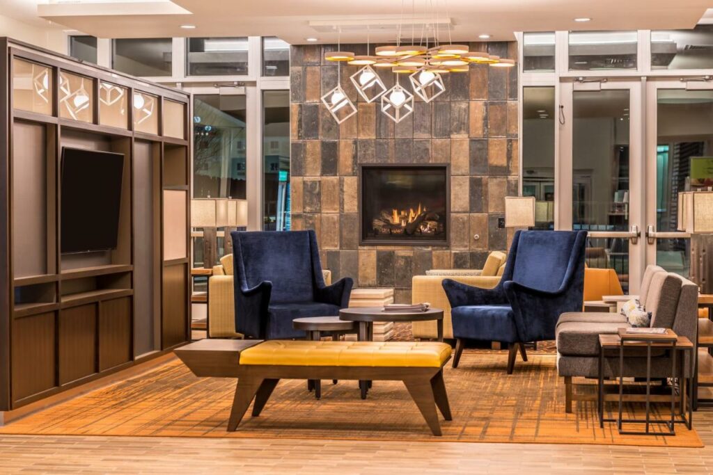 Lounge area in the Holiday Inn Joplin with comfy chairs, cool lighting fixtures, and a fireplace.