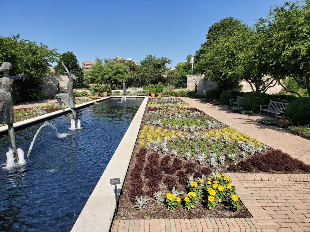 Colorful garden with a fountain with statues of girls playing.