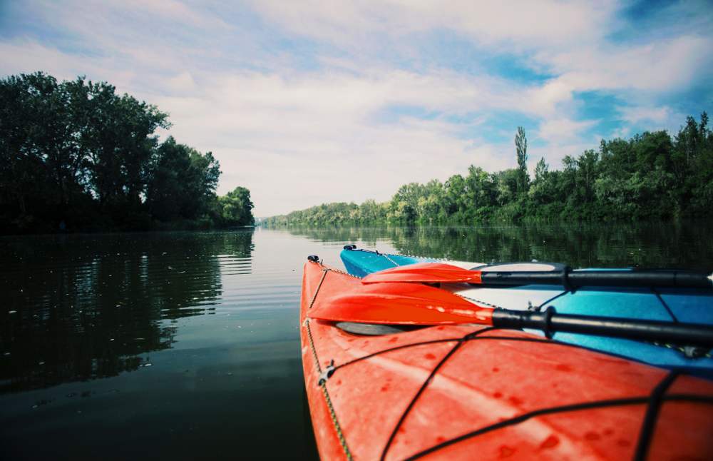 red kayak in foreground on calm blue waters Iowa lakes