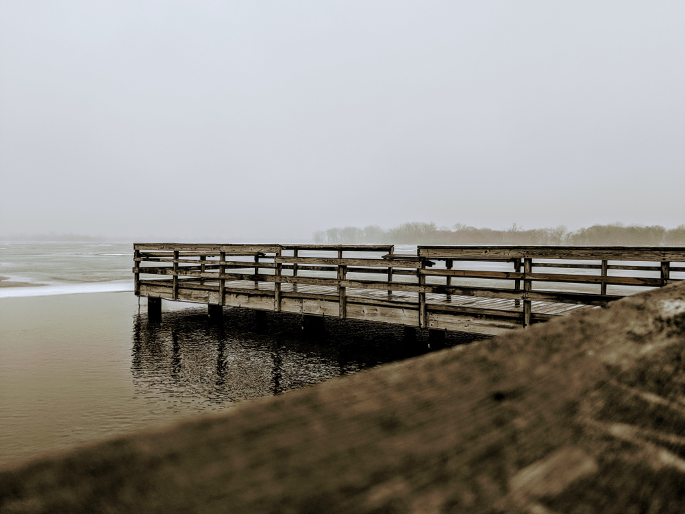 A wooden dock in a lake on a foggy morning