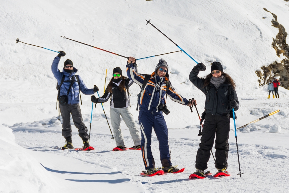 A group of friends snowshoeing next to a snow covered hill