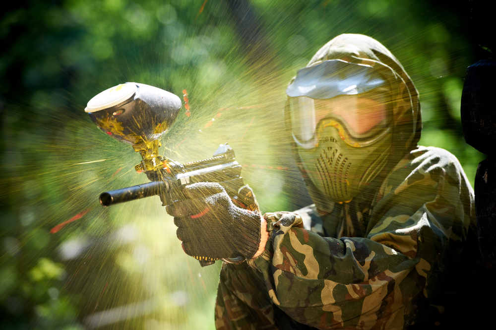 paintball sport player wearing protective mask aiming gun and shotted down with paint splash in summer. The article is about thgins to do in Logan, Ohio