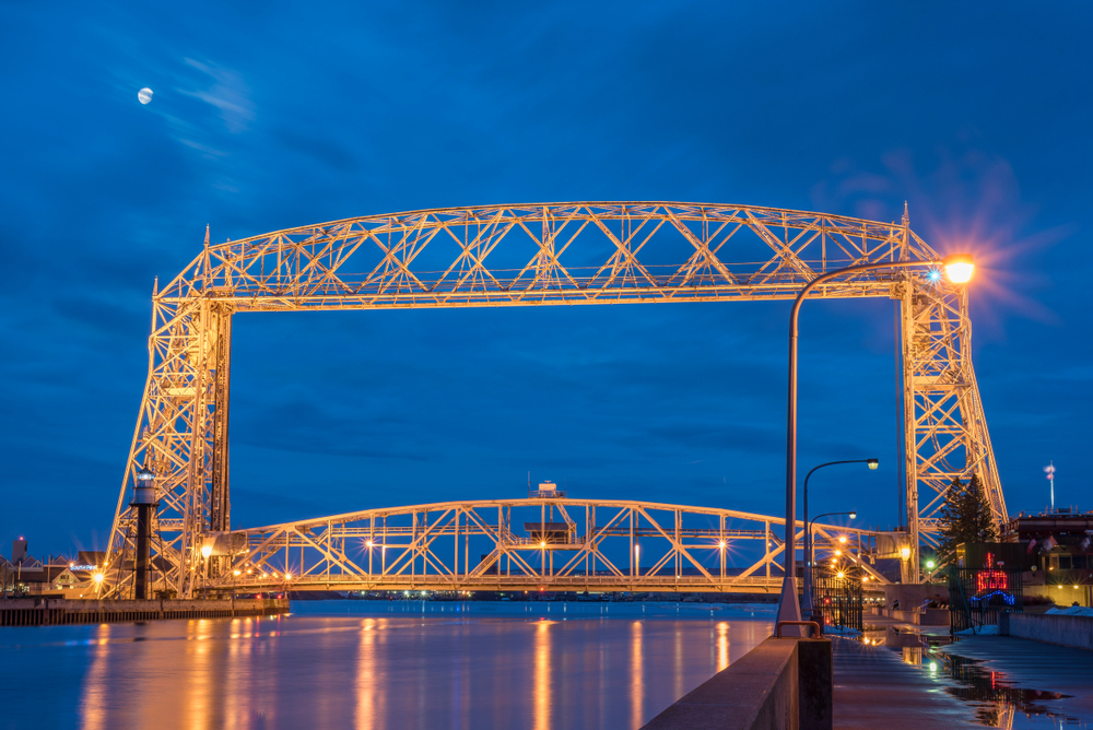 The Aerial Lift Bridge lit up orange at night with lights reflected in the water.
