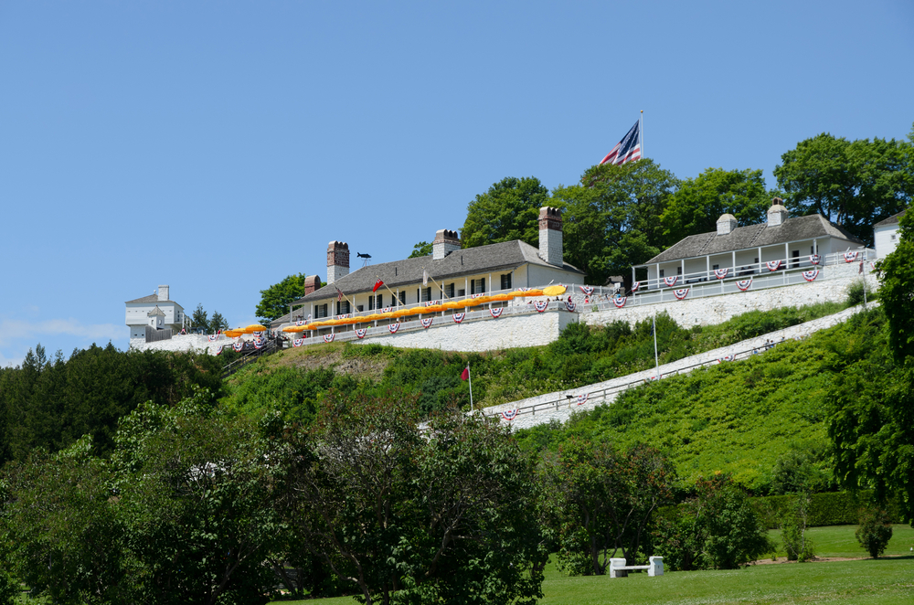 View of historic buildings at Fort Mackinac from the bottom of a green hill.