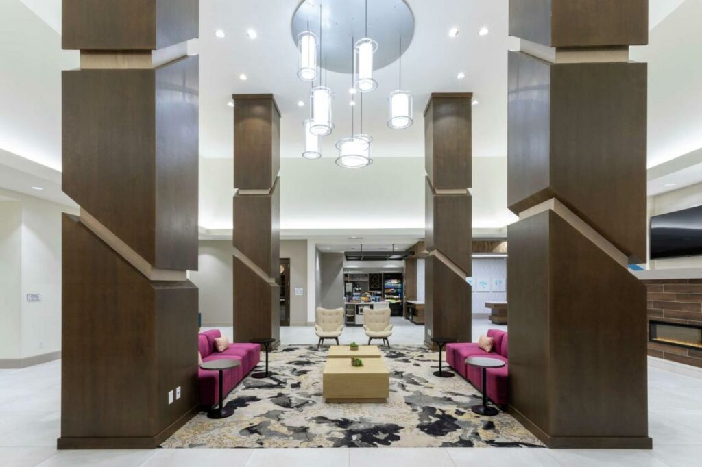 Stylish hotel lobby sitting area with square pillars and hanging lighting fixtures.
