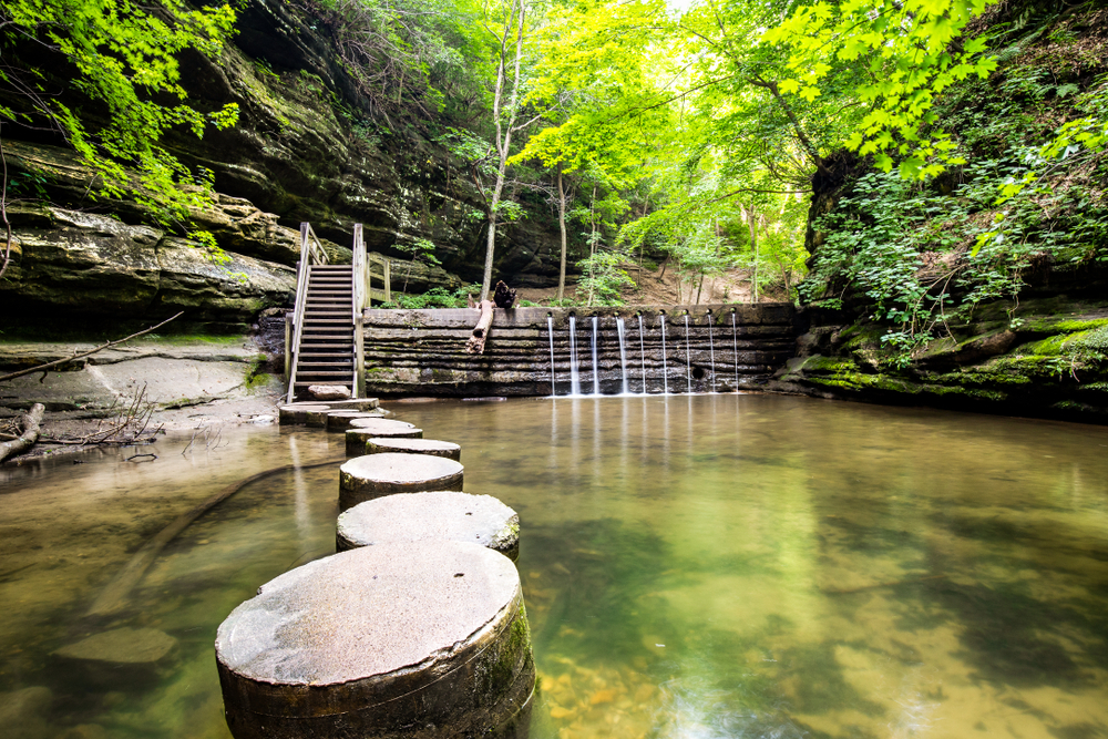 concrete stepping stones leading to a staircase beside a waterfall