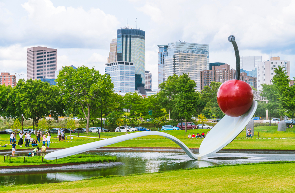 The giant Spoonbridge and Cherry sculpture over a small pond with the Minneapolis skyline in the background.
