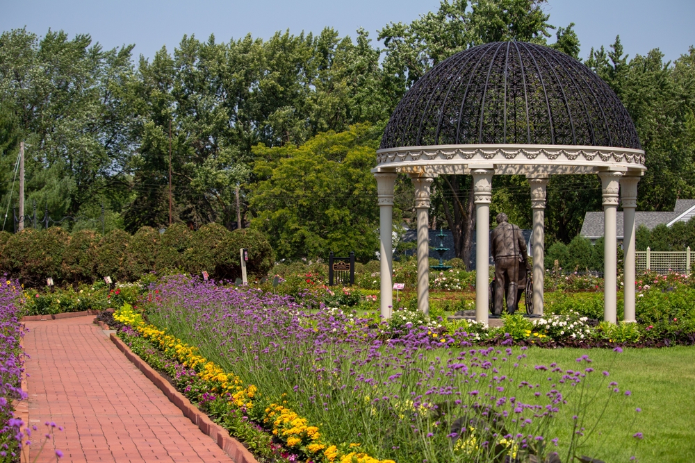 Red brick pathways lined with colorful flowers and a white and metal gazebo.