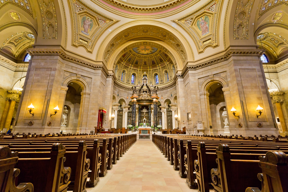 Inside the Cathedral of Saint Paul with high ceilings covered in paintings and lines of pews.