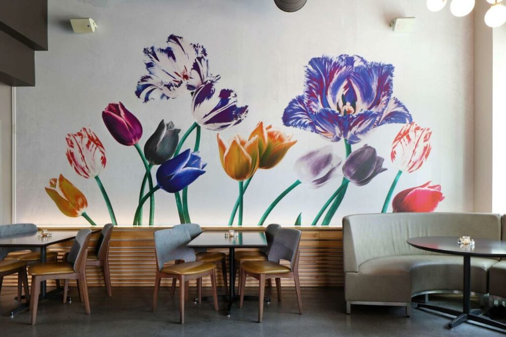Dining area with a mural of tulips on the wall at the Tulyp hotel.