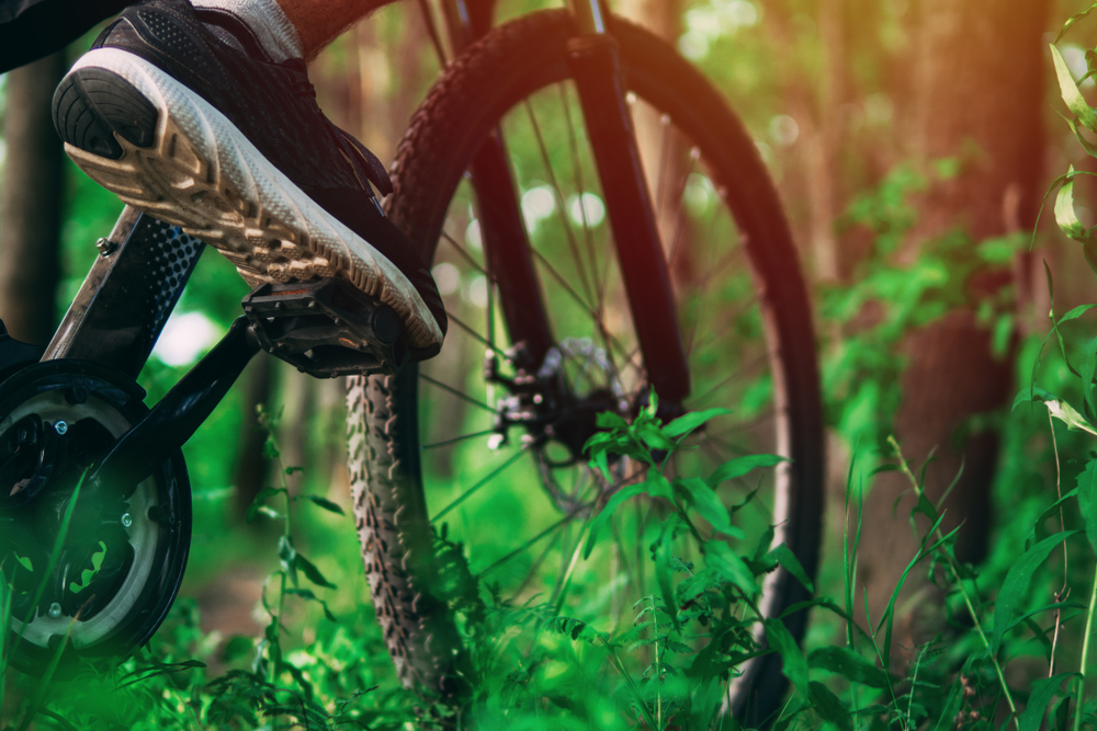 Bike going through the woods with a lcose up on the type and pedals. 