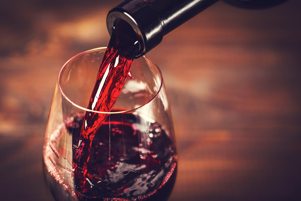 Close up of red wine being poured into a glass.