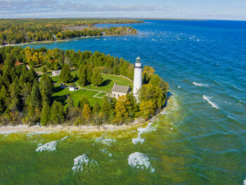 Wisconsin white lighthouse surrounded by sandy beacvh and blue waters