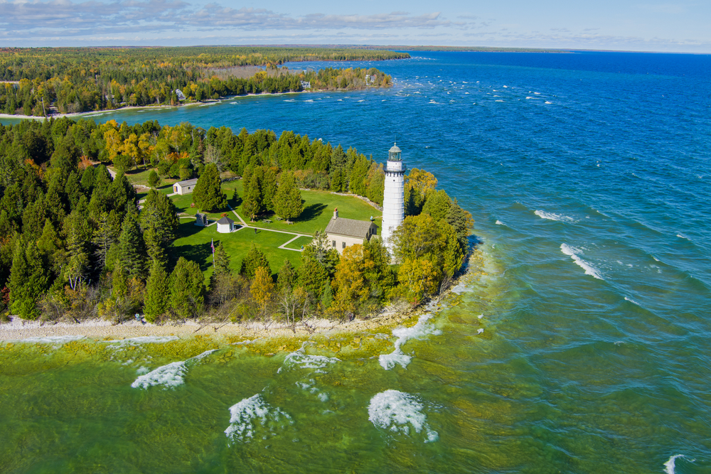 Wisconsin white lighthouse surrounded by sandy beacvh and blue waters