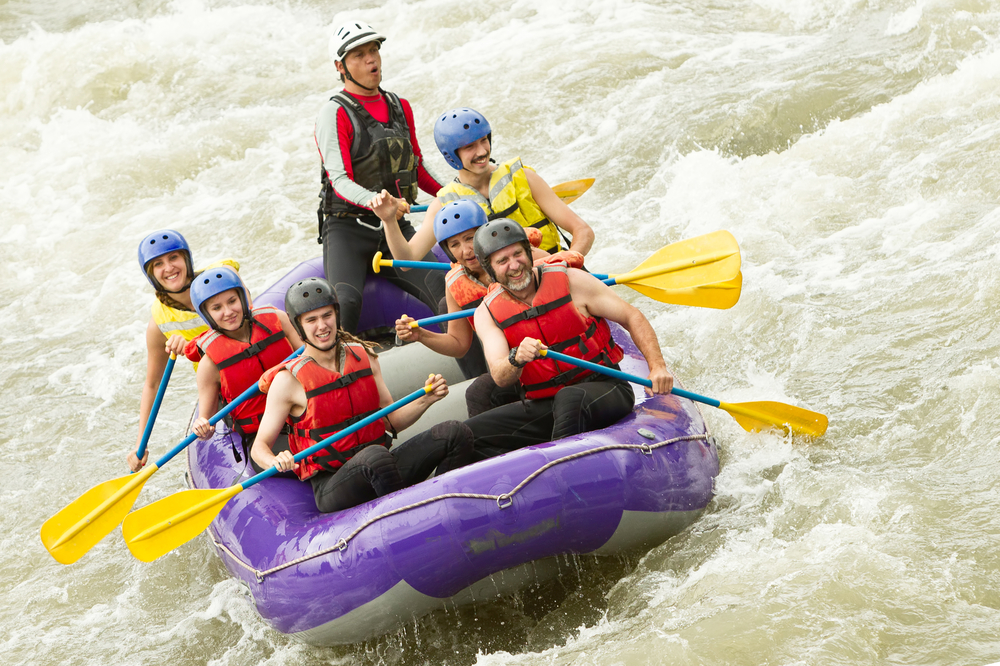 A group of people having fun whitewater rafting in a rushing river. 