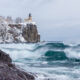 waves rolling onto the shoreline and a cliff with a lighthouse covered in snowy trees winter in minnesota