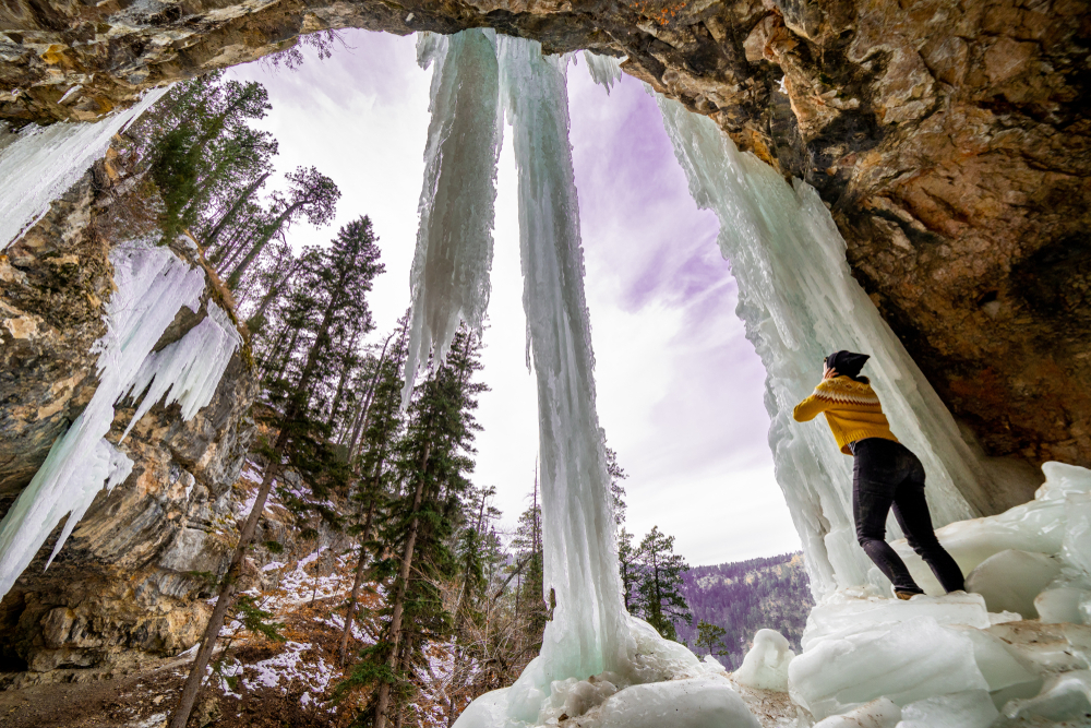 Girl standing under frozen waterfall in Spearfish, South Dakota. One of the Midwest winter getaways. 