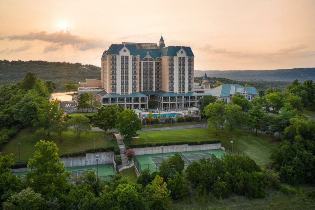 view of a tall hotel building with an outdoor swimming pool surrounded by greenery