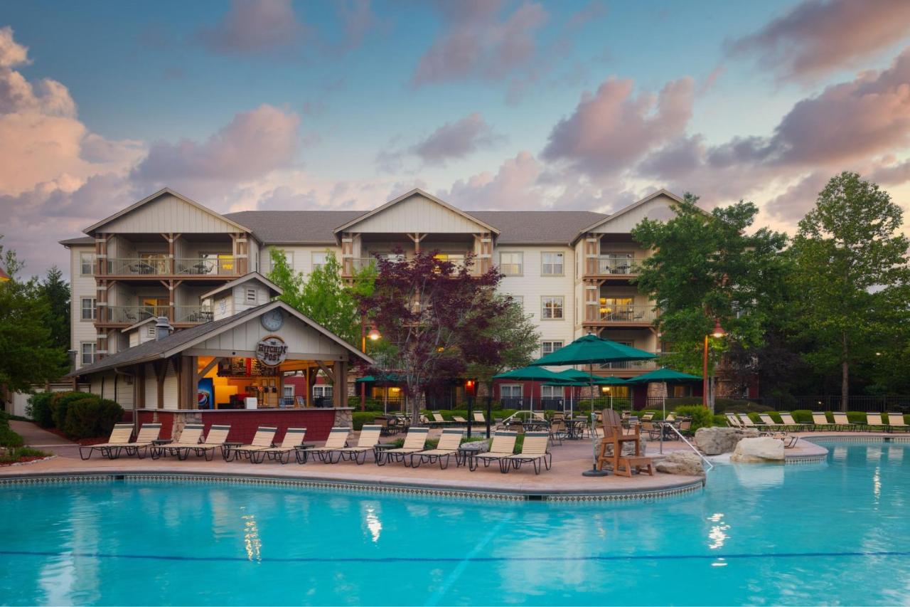 Exteriors of a hotel with an outdoor swimming pool surrounded by trees branson family resorts