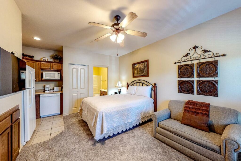 carpeted room with a bed with white covers and sofa and other amenities