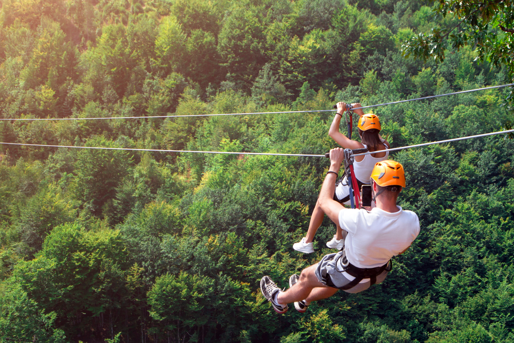 a man and woman ziplining amidst trees things to do at lake of the ozarks