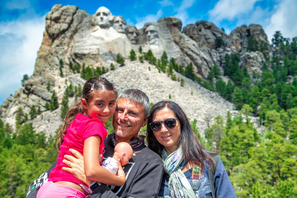 A happy family of three people visiting Mt Rushmore, South Dakota. One of the vacations for families in the midwest. 