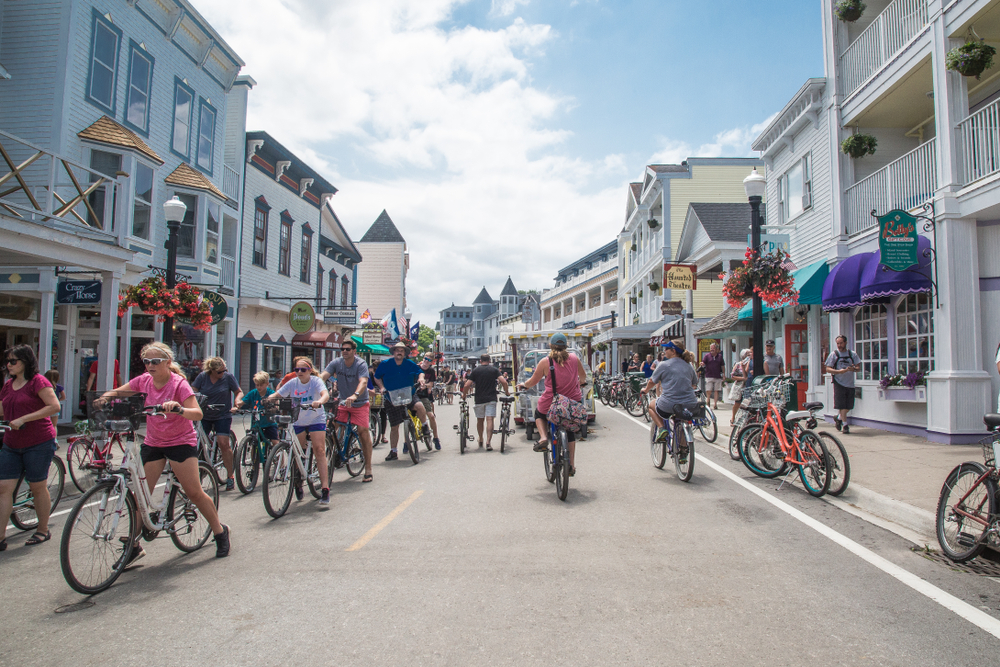 Tourists on bicycles crowd the main downtown street over the holiday. Storefronts, hotels, restaurants and other buildings line both sides of the road. One of the vacations in the midwest for families