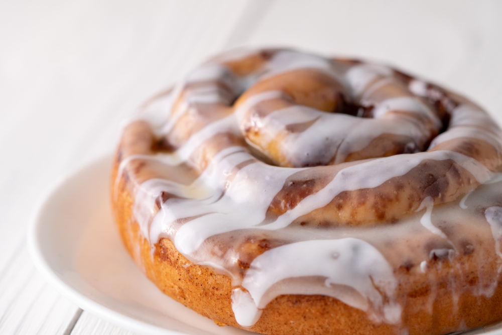 Large gourmet frosted cinnamon roll on white farmhouse table