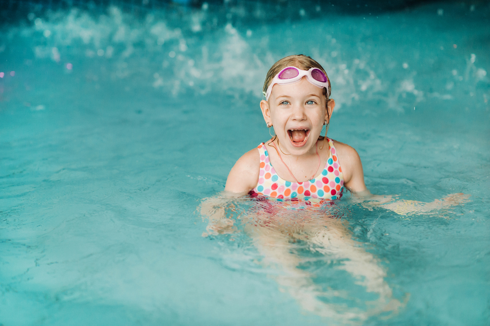 Kids play in aqua park. Girl having fun sat down in the water 