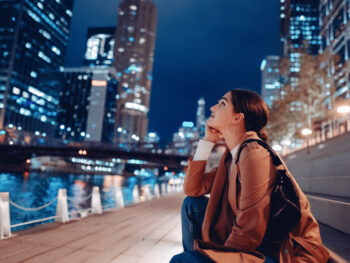 young woman wearing a light jacket at night admiring the buildings what to wear in chicago