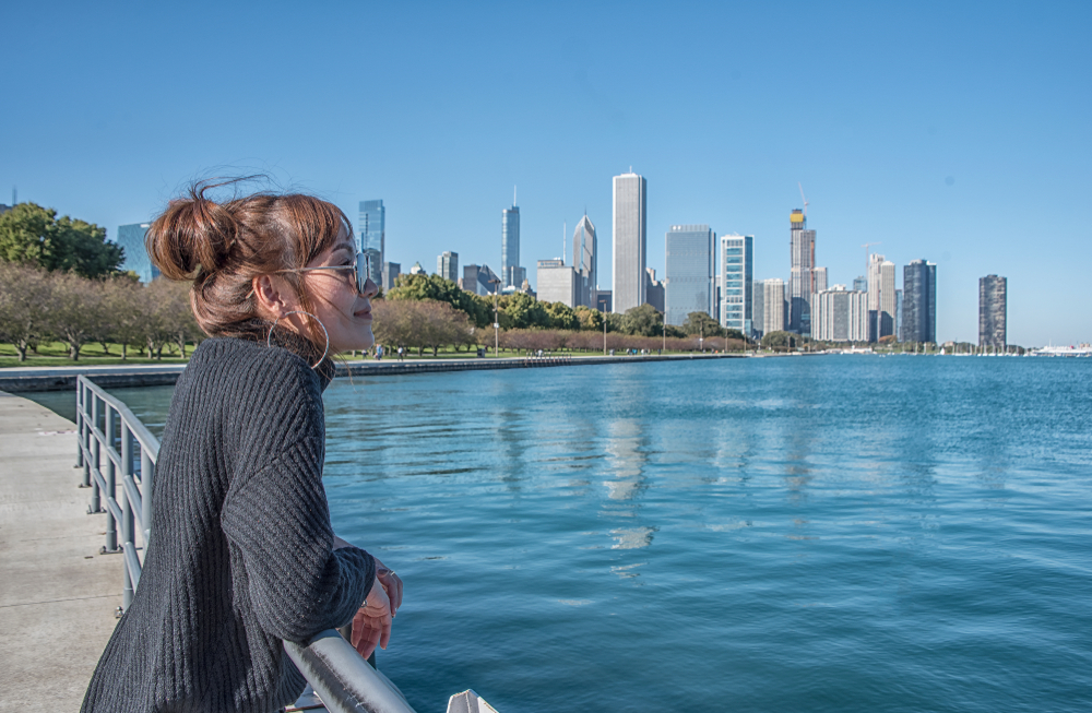 woman looking at the river from a bridge with buildings in the backdrop what to wear in chicago