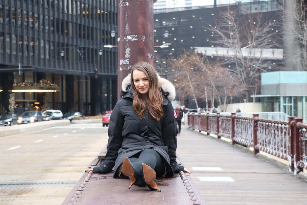 young woman wearing a parka jacket with fur hood, thick leggings, and heels