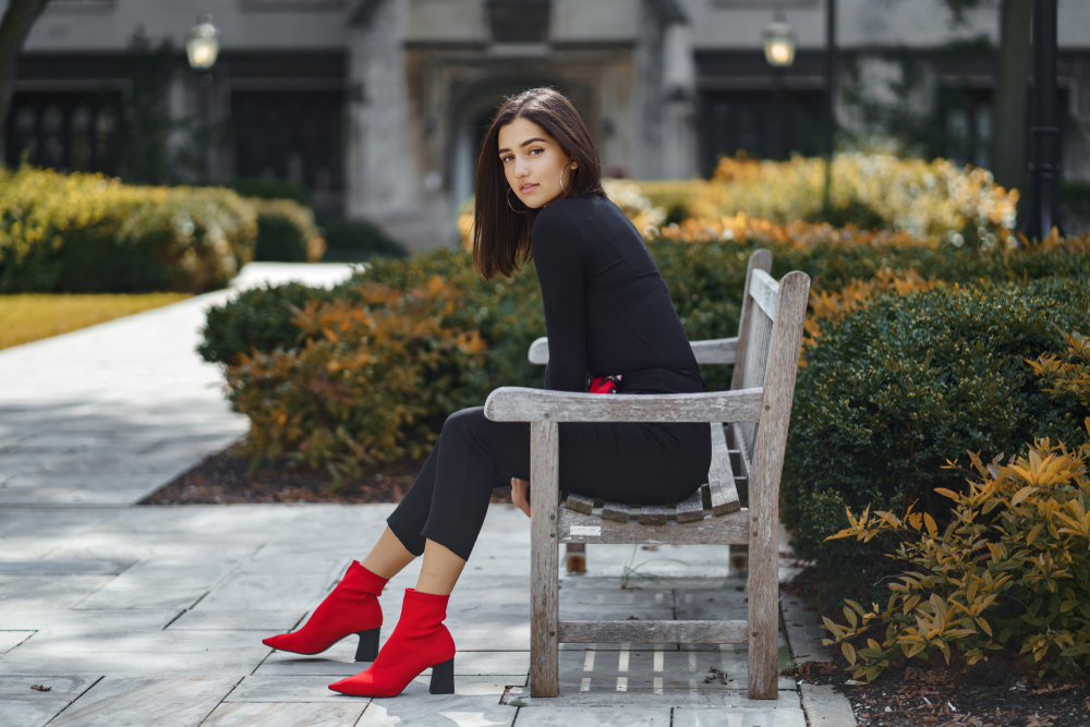 girl sitting on a bench wearing black outfit with red boots what to wear in chicago in the fall