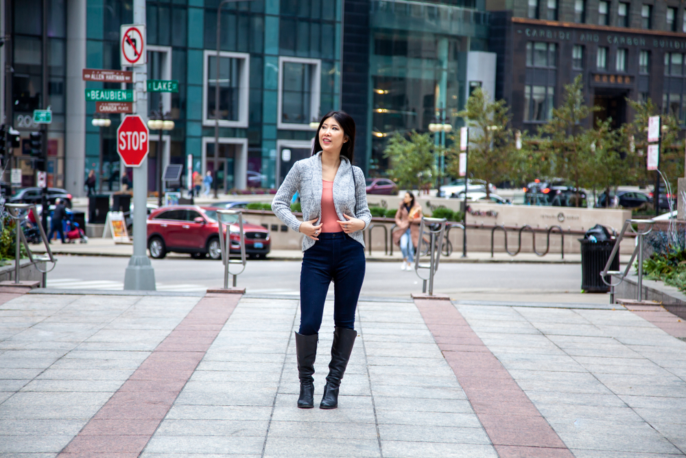 girl wearing a sweater and jeans with boots in front of buildings