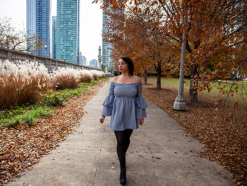 woman wearing blue top with stockings in a park with autumn leaves what to wear in chicago in the fall