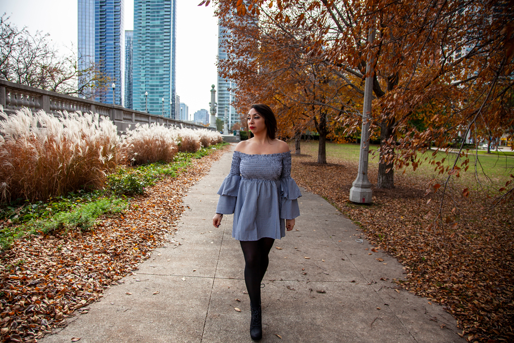 woman wearing blue top with stockings in a park with autumn leaves what to wear in chicago in the fall