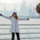 woman smiling in white jacket holding a balloon with Happy New Year in front of the buildings and ocean what to wear in chicago in the winter