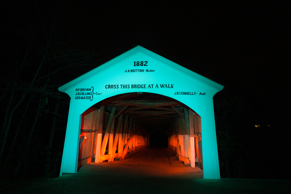 narrow covered bridge lit up with blue light at night