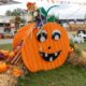 pumpkin face carved on a wooden wheel with fall decorations all around midwest fall festivals