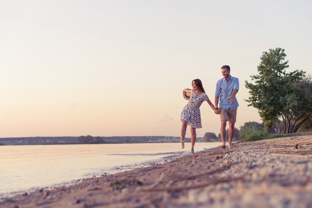 Couple walking on the beach at sunset. Sunset. The article is about Midwest destinations.