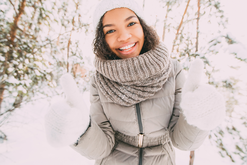 Happy teenage girl showing thumbs up in winter