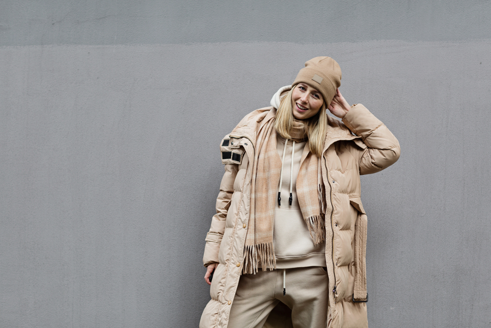 Woman standing outdoor wearing warm weather clothes. Hat and coat.
