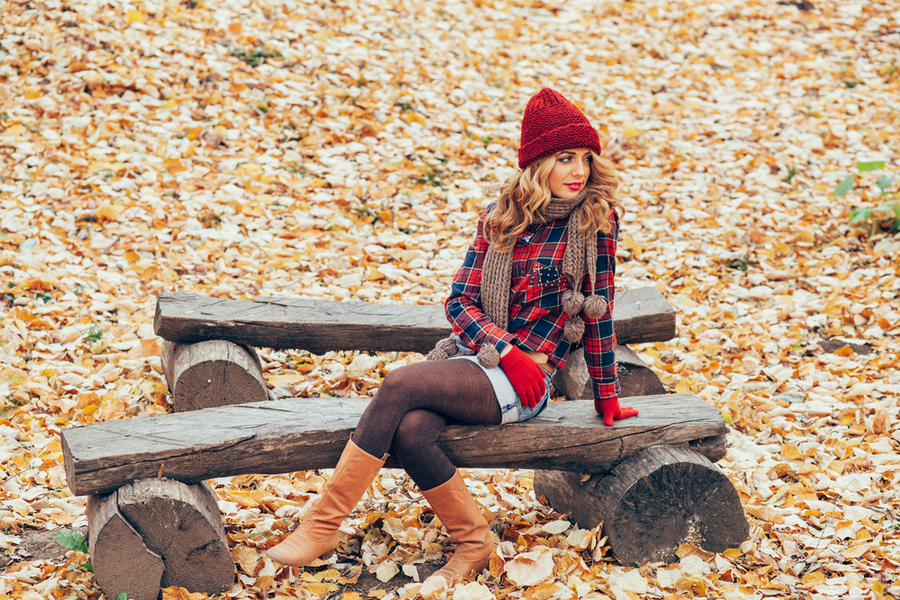 Autumn Fashion girl in plaid shirt sitting on bench in woods. Article is about Montana fall outfits.