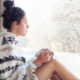 Caucasian woman looking out window at snowy trees