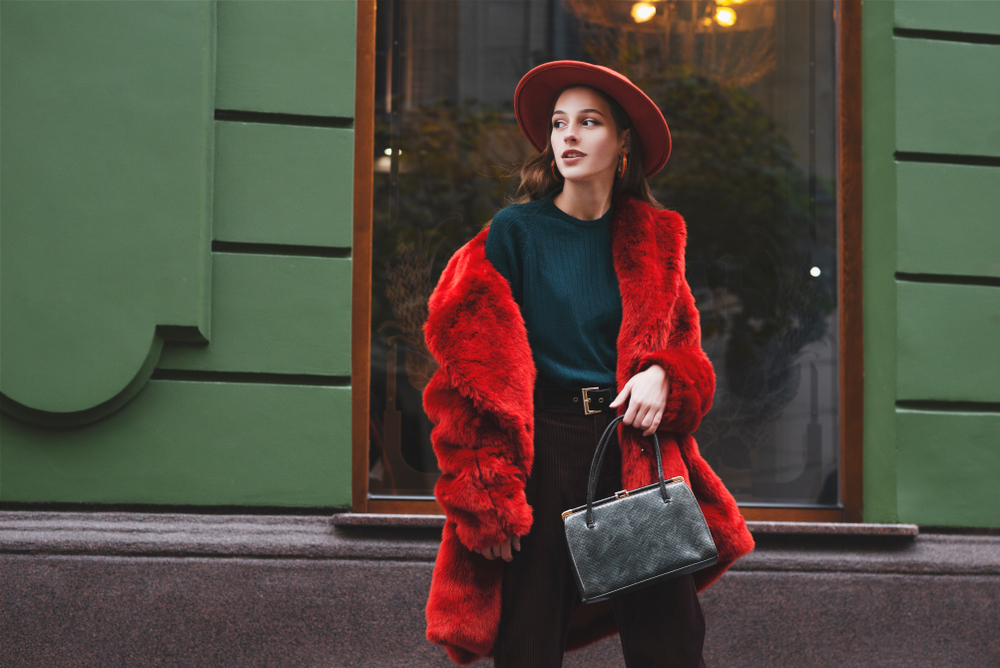 women in red coat and hat walking across the street,